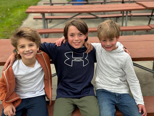 Three friends sitting on a picnic table.