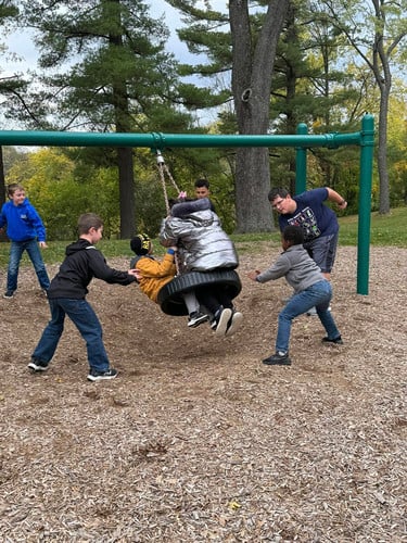 Montessori students play on the tire swing.