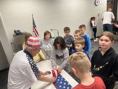5th grade students learn how to fold a flag from local veterans.