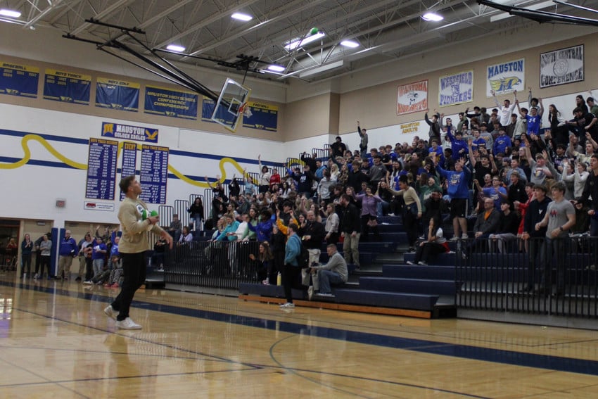 A Green Bay Packer gets ready to throw a prize into a crowd of students.
