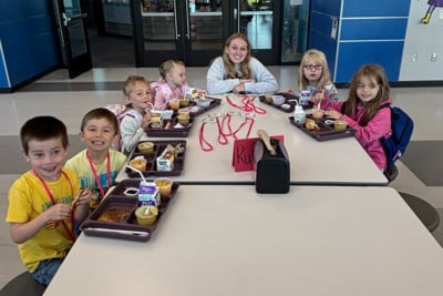 Students sit around a table with food.