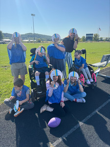 Students with paper plate helmets on the track outside.