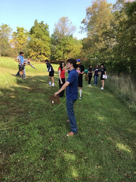 Students are outside with measuring tapes and other equipment.