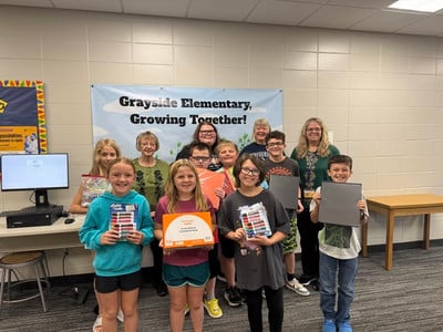 Students and adults stand in a hallway with school supplies.