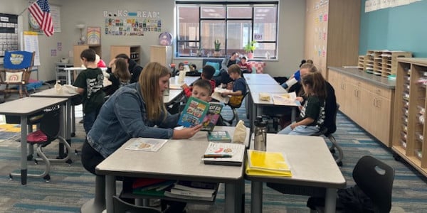 Teacher and students read together in a bright, decorated classroom during a literacy session..