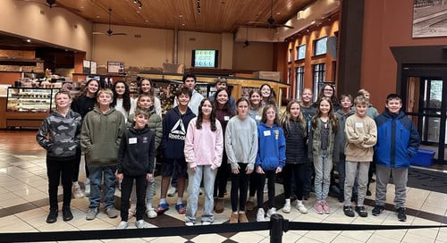 Group of middle school students standing in a large wood-paneled lobby for a math competition.