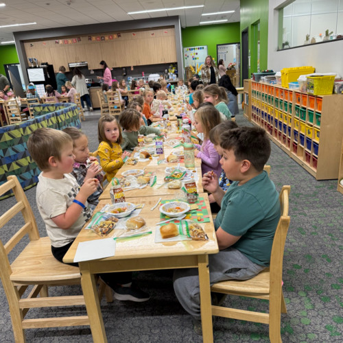 Elementary students sitting together at long tables eating a communal holiday or Thanksgiving meal.