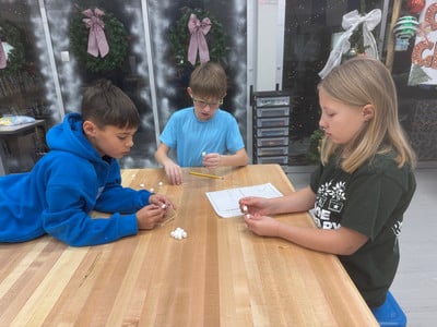 Students building structures with marshmallows and toothpicks during a classroom activity.