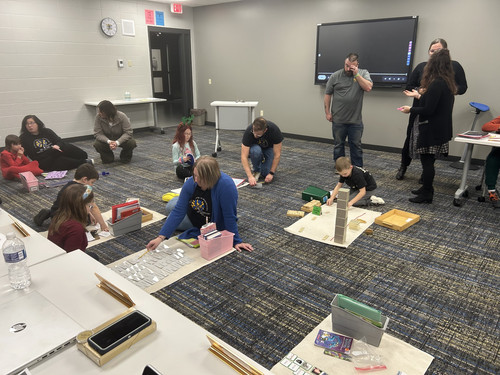 Students and staff participating in a Montessori-style educational demonstration during a meeting.
