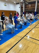 Students and staff cheer as someone gets a pie in the face during a school spirit event.