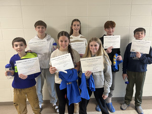 Six students stand together in a hallway holding their 