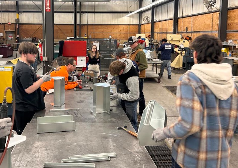 Students in a workshop carefully measures for a construction project.