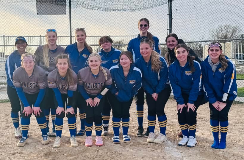 A group of girls in blue and gold softball uniforms posing together on a dirt infield.