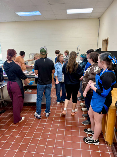 iLEAD students prepare food together around metal counters in a school instructional kitchen.